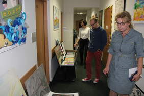 Pokaż zdjęcie: Zdjęcie korytarza biurowego, na krzesłach i podłodze poustawiane są prace plastyczne, komisja plastyczna przygląda się pracom, w skład komisji wchodzą trzy kobiety i mężczyzna