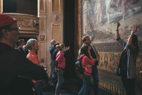 Pokaż zdjęcie: Grupa osób stoi na scenie teatru i przypatruje się kobiecie która gestykuluje rękami.