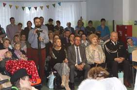 Pokaż zdjęcie: Zdjęcie zaproszonych osób siedzących na krzesełkach i oglądających przedstawienie jasełkowe