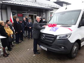 Pokaż zdjęcie: Mężczyzna przecina wstęgę na masce autobusu. 