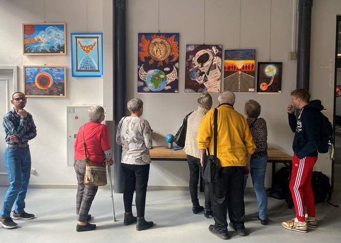 Pokaż zdjęcie: Na zdjęciu widać  osób oglądających 7 obrazów i rzeźby