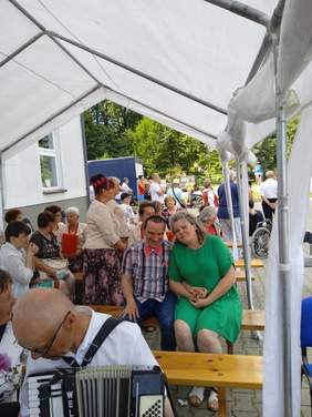 Pokaż zdjęcie: Pod namiotem siedzi duża grupa osób i ogląda występy artystyczne