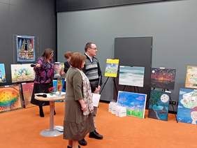 Dyrektor Kujawsko-Pomorskiego Oddziału PFROn Aleksandra Gierej podcza wręczania nagród. W tle stoi jeden z uzcestnikó, a za nim wodoczne są prace plastyczne