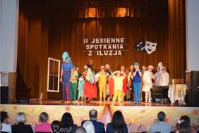 Pokaż zdjęcie: na scenie grupa przebranych dzieci śpiewa i tańczy.