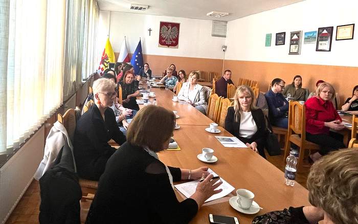 Na sali, przy stołach siedzą i rozmawiaja uczestniczki spotkania i prelegentki