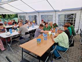 przy stołach w namiocie piknikowym siedzą uczestnicy imprezy