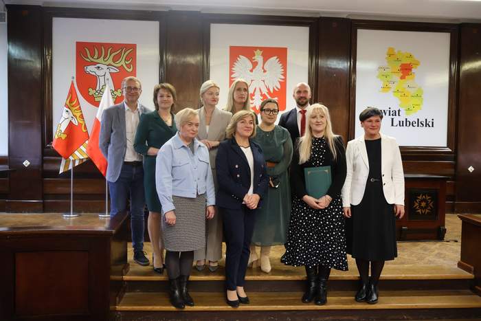 Pokaż zdjęcie: Na schodach w starostwie do pamiątkowej fotografii pozuje 10 osób. 