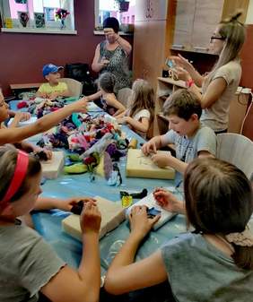 Pokaż zdjęcie: Dzieci siedzą wokół stołu i wykonują prace plastyczne