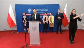 Pełnomocnik Wojewody Kujawsko-Pomorskiego do spraw Osób Niepełnosprawnych - Paweł Bednarski podczas konferencji prasowej przy mównicy, obok tłumacz języka migowego