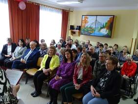 Pokaż zdjęcie: Zdjęcie uczestników spotkania siedzących na krzesełkach ustawionych w rzędach.