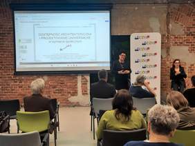 Pokaż zdjęcie: W sali konferencyjnej siedzą na krzesłach ludzie. Słuchają prelekcji, którą prowadzi Zastępca Prezesa Zarządu PFRON Bożena Borowiec. 