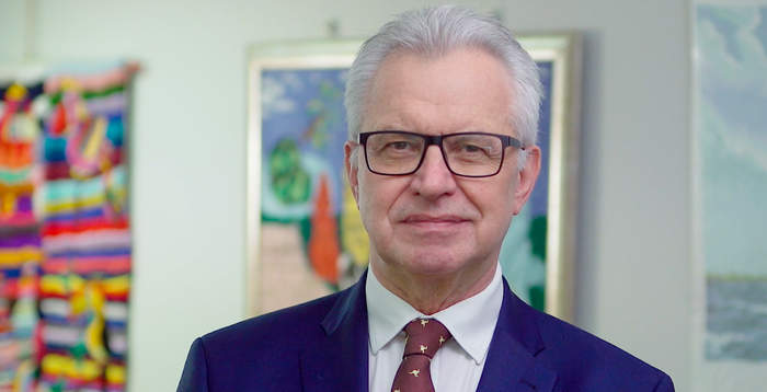 Pokaż zdjęcie: mężczyzna na tle kolorowych prac plastycznych