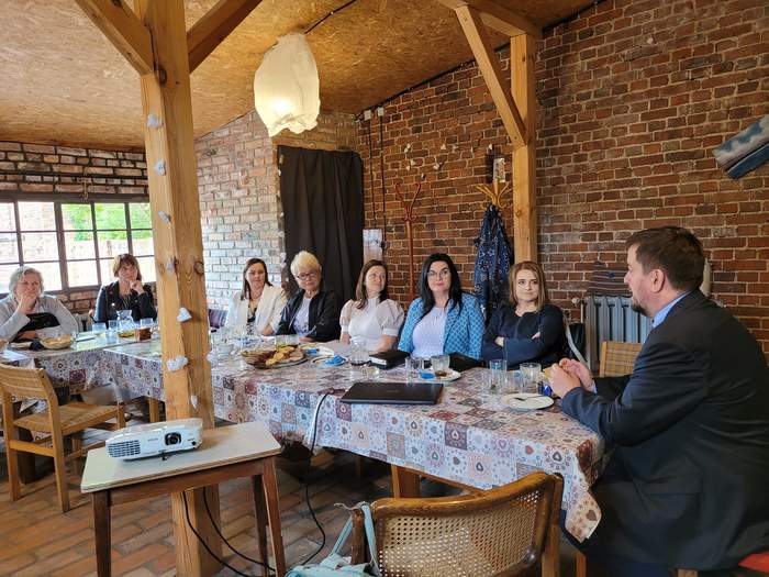 Pokaż zdjęcie: Przy stole, w pomieszczeniu z cegieł siedzą Kierownicy lubuskich WTZ, razem z nimi Dyrektor Oddziału PFRON w Zielonej Górze
