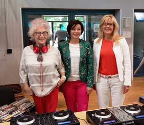 Pokaż zdjęcie: Trzy osoby stoją przy konsoli didżeja: Wirgnia Szmyt - Dj Wika, Katarzyna Łęgiewicz - Burmistrz Dzielnicy Ochota m. st. Warszawy, Aleksandra Włodarska Prezes Fundacji ECHO