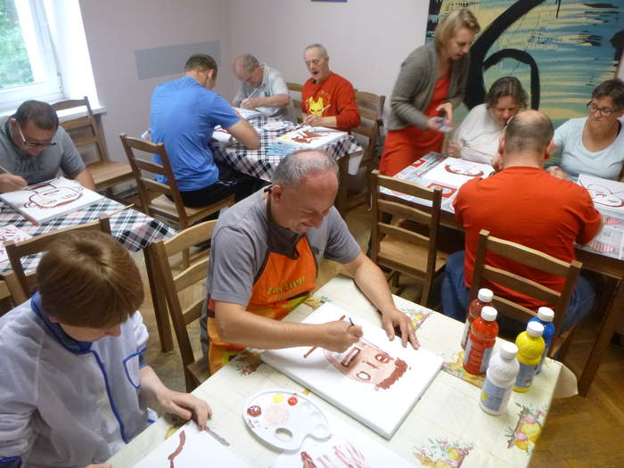 Pokaż zdjęcie: Uczestnicy ŚDS Caritas podczas zajęć plastycznych - dorosłe osoby z niepełnosprawnościami malują farbami portrety