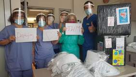 Pokaż zdjęcie: PTWM dziękuje za wsparcie - na zdjęciu pracownicy w maseczkach, przyłbicach w rękach trzymają kartki z podziękowaniami