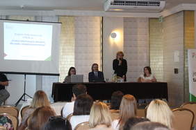 Pokaż zdjęcie: W sali konferencyjnej za stołem prezydialnym siedzą cztery osoby, trzy kobiety i jeden mężczyzna, po lewej stronie ekran z prezentacją