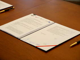 Pokaż zdjęcie: Na stole, w eleganckiej teczce leży podpisana umowa.