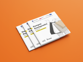 Trzy broszury "Kompas dostępności" na pomarańczowym tle