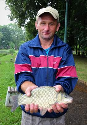 Pokaż zdjęcie: Wędkarz podczas zawodów ze złapanym karasiem