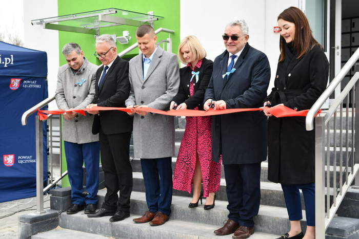 Pokaż zdjęcie: Na schodach bursy szkolnej stoi w rzędzie 6 osób, które uroczyście przecinają wstęgę.