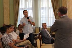 Pokaż zdjęcie: Uczestnik spotkania z mikrofonem udziela się w dyskusji