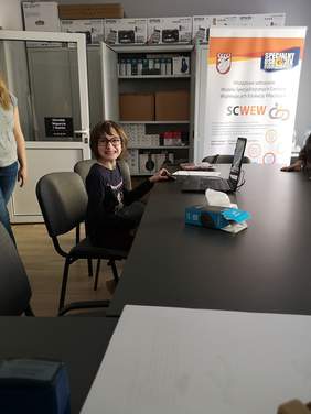 Pokaż zdjęcie: Uśmiechnięta dziewczynka siedzi przy laptopie