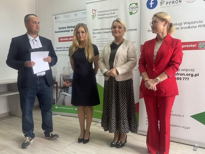 Pokaż zdjęcie: Na tle banerów z logo PFRON stoją 3 kobiety i 1 mężczyzna, który prowadzi spotkanie