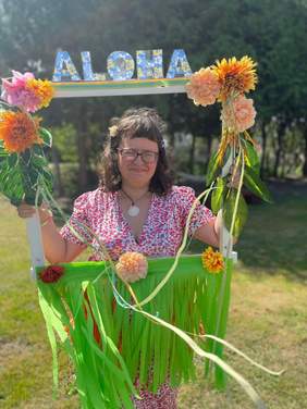 Pokaż zdjęcie: Kobieta ubrana w sukienkę z kolorowymi elementami i wiankiem na głowie w stylizacji kobiet w Polinezji