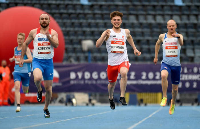 Pokaż zdjęcie: Trzech mężczyzn biorących udział w biegu na profesjonalnej bieżni sportowej