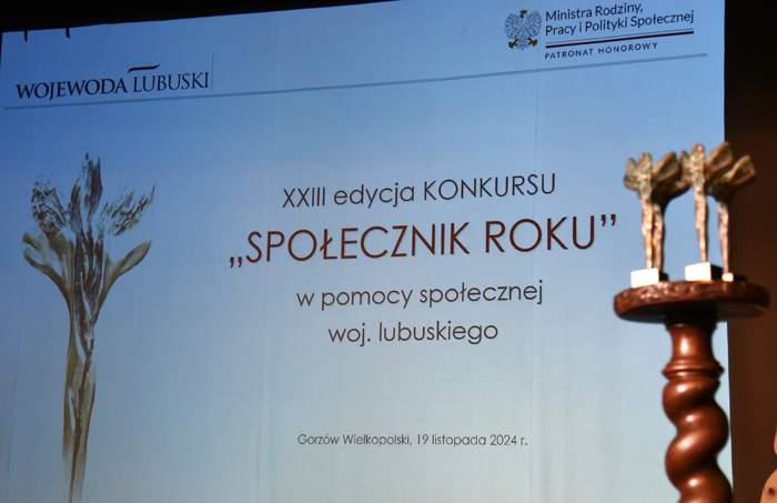 Pokaż zdjęcie: Widoczny slajd z opisem Gali rozdania nagród "Społecznik Roku", widoczne też statuetki dla zwycięzców