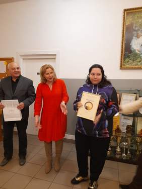 Pokaż zdjęcie: Kobieta prezentuje dyplom trzymając go w dłoni