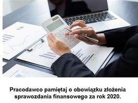 Pokaż zdjęcie: na zdjęciu biurko na którym leży laptop oraz dokumenty do sprawozdań finansowych, na pierwszym tle widać ręce osoby która trzyma w nich kalkulator i długopis  