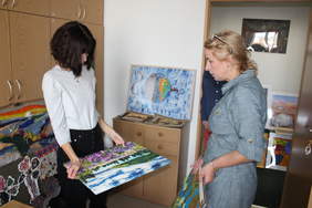 Pokaż zdjęcie: Zdjęcie pokoju biurowego, na krzesłach i podłodze poustawiane są prace plastyczne, komisja plastyczna przygląda się pracom, w skład komisji wchodzą trzy kobiety i mężczyzna