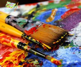 Pokaż zdjęcie: Zdjęcie jest grafiką. Pędzle leżą na palecie z farbami. Ilustracja jest bardzo barwna. W lewym górnym rogu umieszczone jest logo konkursu: "Sztuka jak balsam".  