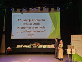 Pokaż zdjęcie: Na tle prezentacji, na scenie, stoją obok siebie Wicewojewoda Lubuski Tomasz Nesterowicz i Dyrektor Oddziału Lubuskiego PFRON Elżbieta Miernik-Krukurka