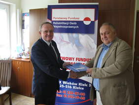 Pokaż zdjęcie: Andrzej Michalski Dyrektor Oddziału Świętokrzyskiego PFRON wręcza umowę  Wicestaroście Powiatu Opatowskiego  Gustawowi Saramańskiemu 