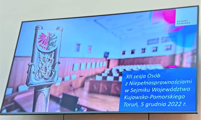 Tablica z widokiem na salę obrad i napis informujący o sesji