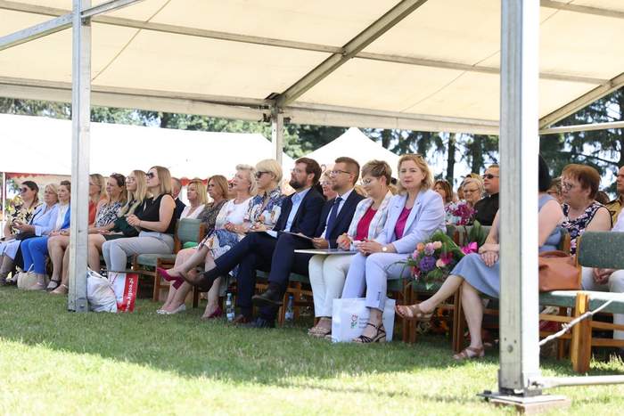 Pokaż zdjęcie: na trawie pod namiotem, na krzesełkach siedzą zaproszeni goście