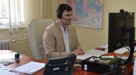 Pokaż zdjęcie: Mężczyzna siedzi przed komputerem w słuchawkach