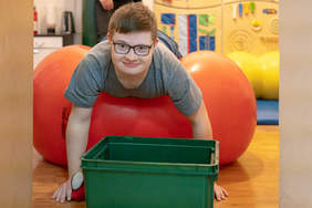 Pokaż zdjęcie: Podopieczny Fundacji w trakcie zajęć. Na zdjęciu młody, uśmiechnięty podopieczny podczas ćwiczeń.