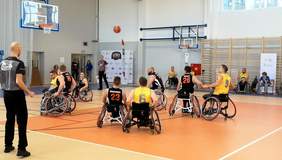 Pokaż zdjęcie: na sali sportowej osoby na wózkach inwalidzkich grają mecz koszykówki.