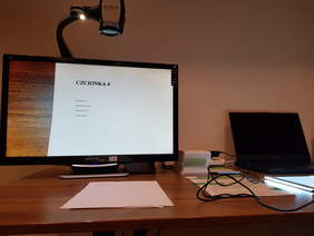 sprzę elektroniczny duży monitor z powiększalnikiem, obok laptop