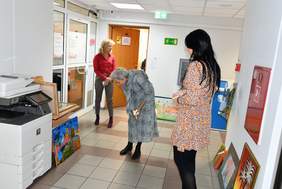 Korytarz, pod ścianami ustawione prace plastyczne. Na pierwszym planie Pani Dorota Jankowska trzymająca notatki, w głębi stoi Pani Katarzyna Haber przyglądająca się jednej z ocenianych prac. W głębi stoi Pani Bogna Jarzemska-Misztalska.