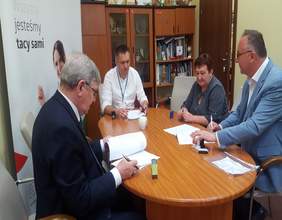 Pokaż zdjęcie: na zdjęciu gainet Dyrektora Oddziału po lewej baner z logo PFRON po środku biurko o owalnym kształcie na którym są dokumenty podpisywane przez osoby reprezentujące instytucję PFROn i Gminę Szadek