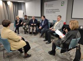 Pokaż zdjęcie: Kobiety oraz mężczyźni siedzą w sali konferencyjnej, rozmawiają.