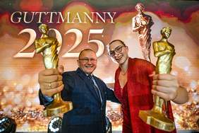 Pokaż zdjęcie: Faustyna Kotłowska i Zbigniew Lewkowicz, ubrani na galowo, trzymają w rękach stauetki Guttmannów i są zadowoleni i uśmiechnięci