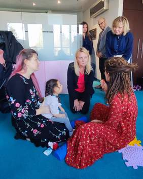 Pokaż zdjęcie: Kobiety siedzące na dywanie wraz z niepełnosprawną dziewczynką