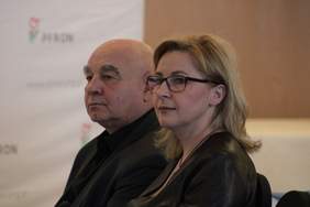 Pokaż zdjęcie: Zdjęcie dwóch osób siedzących na konferencji, zbliżenie na górną część ciała