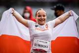Uśmiechnięta Renata Śliwińska trzyma w rękach flagę Polski